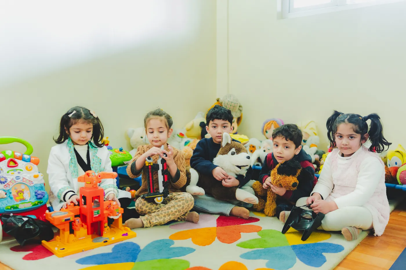 A group of children playing with soft toys together