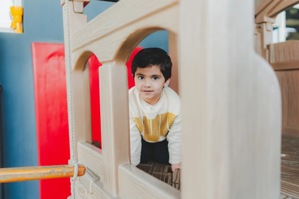 A child climbing through the wooden climbing frame